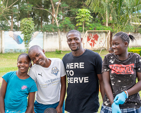 Volunteer standing with youth during a Kenya Relief community program