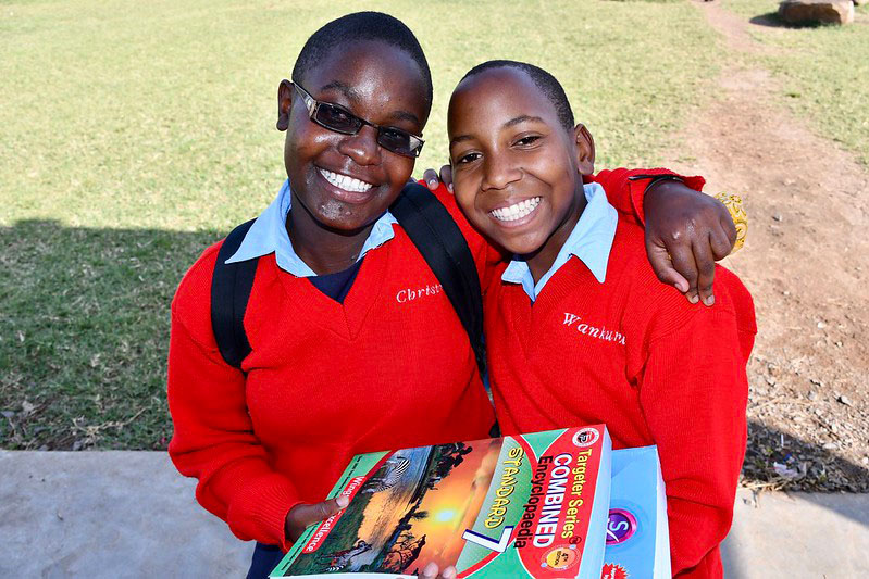 Two smiling students holding their textbooks at Kenya Relief Academy, showcasing a structured and supportive learning environment.
