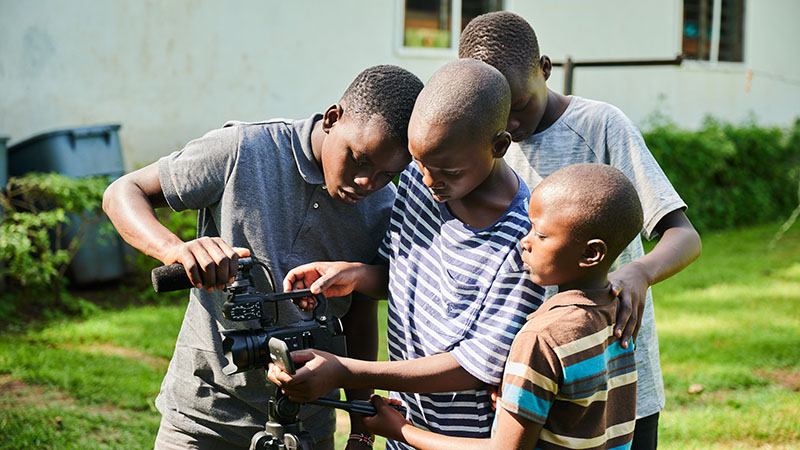 A group of students at Kenya Relief Academy learning how to use a professional video camera for media skills.